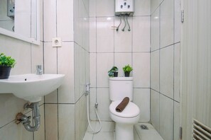 A bathroom with a white sink, toilet, and shower. There are two potted plants on the toilet tank. - Chic Minimalist Studio At Apartment Grand Kamala Lagoon (Bekasi)