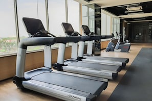 A row of treadmills in a gym with large windows. - Smart Living Studio At Apartment Springwood Residence Tangerang (Tangerang)