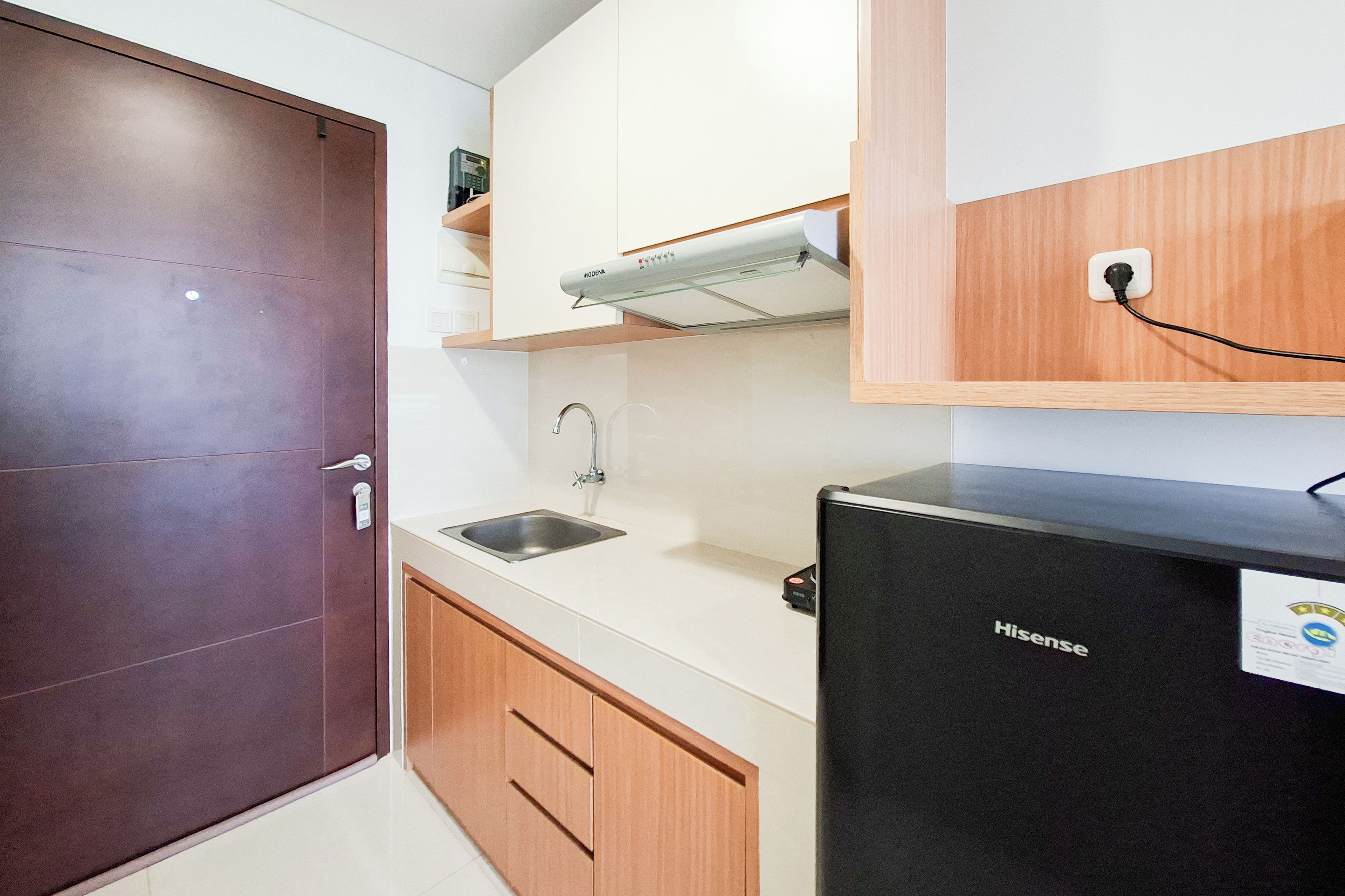 Una cocina compacta con refrigerador, pileta y armarios de madera.