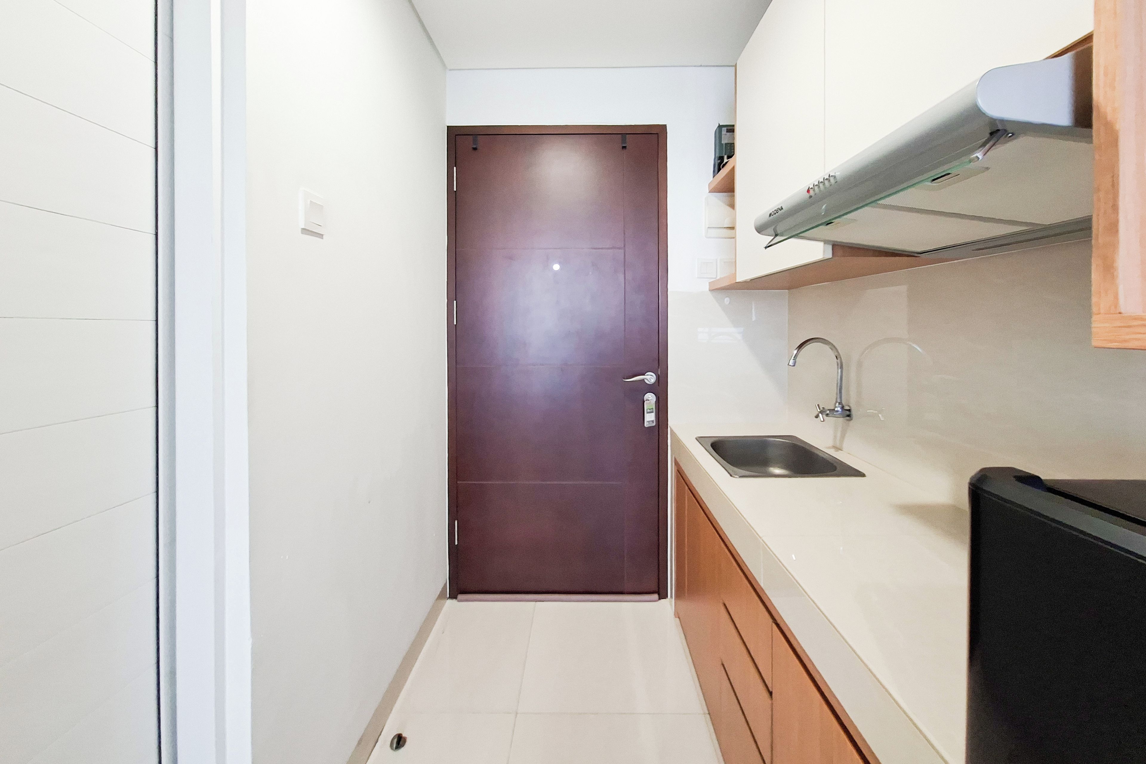 Una cocina estrecha con una puerta marrón, un lavamanos y un microondas.