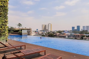 Ein Pool auf dem Dach mit Liegestühlen und Blick auf die Stadt.