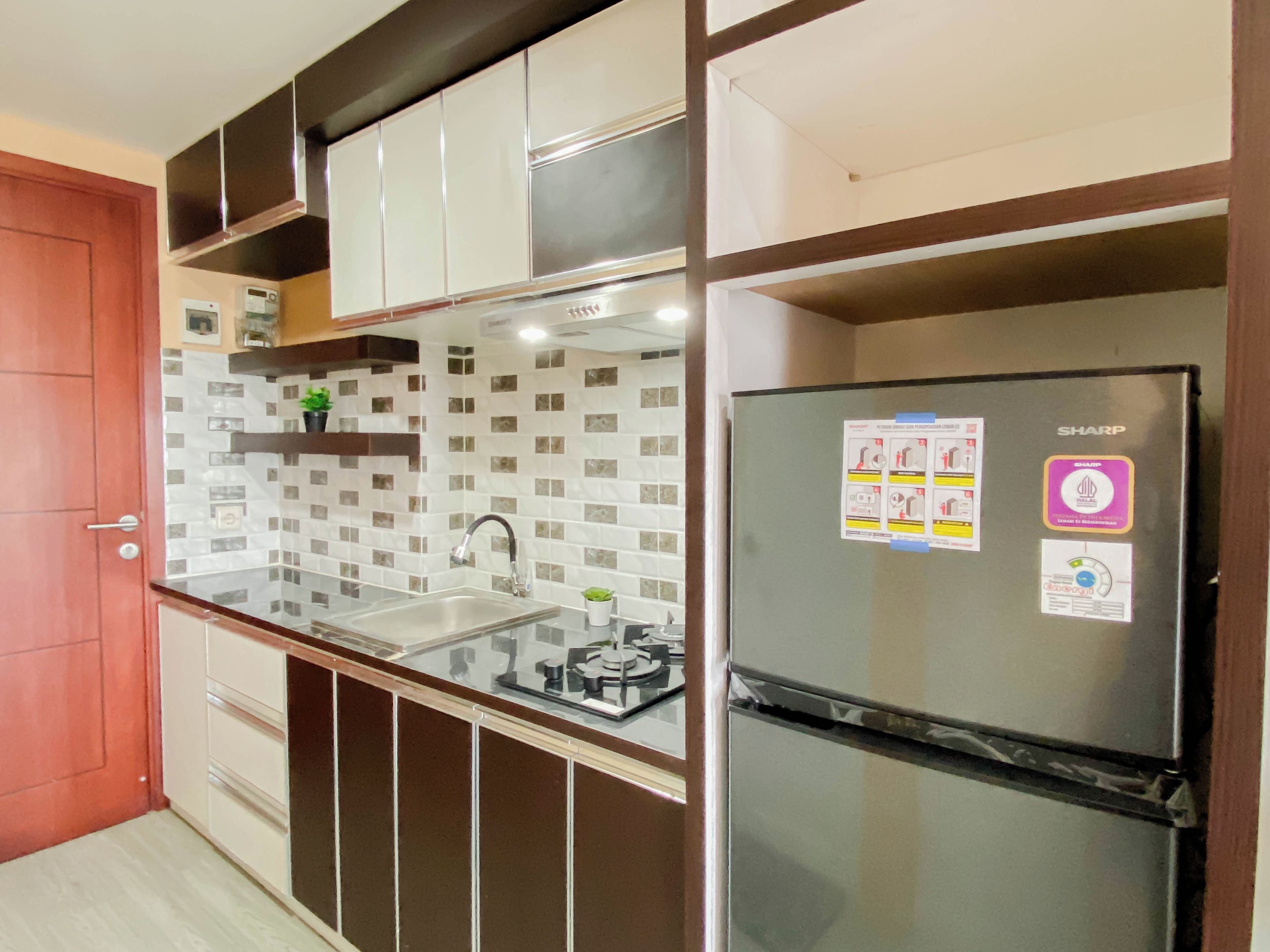 A kitchen with a stainless steel refrigerator, a double sink, and a tiled backsplash.