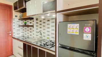 A kitchen with a stainless steel refrigerator, a double sink, and a tiled backsplash.