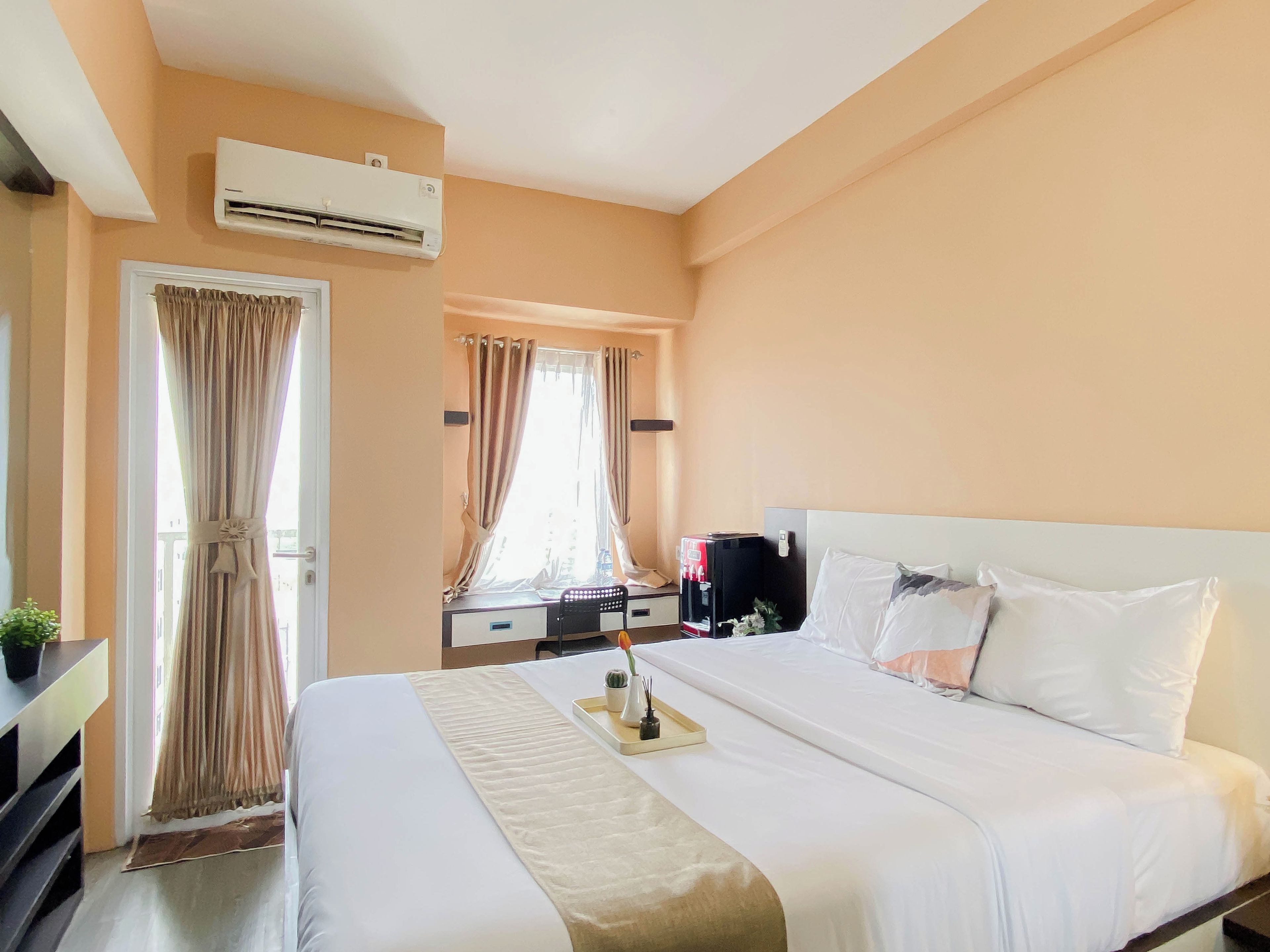 Una habitación de hotel con una cama, un escritorio, aire acondicionado y una ventana con cortinas.