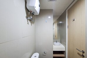 A bathroom with a toilet, sink, and hand dryer. - Neat And Nice Studio Room At Apartment Tree Park City Bsd (Tangerang)
