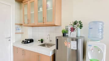 A kitchen with wooden cabinets, a stainless steel refrigerator, a water dispenser, and a sink.