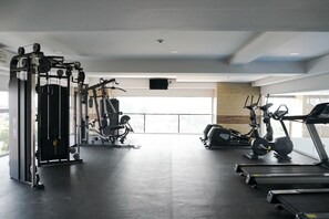 Ein Fitnessstudio mit verschiedenen Trainingsgeräten, darunter Laufband, Crosstrainer und Kraftgeräte.