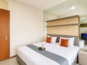 A hotel room with a large bed, a television, and a mirror. - Strategic And Cozy 1Br At Apartment Thamrin Residence (Jakarta)