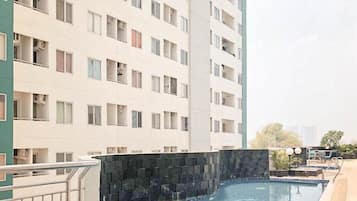 Een meerlaags woongebouw met balkons, een zwembad en een stenen muur.