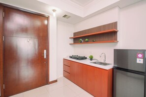 A modern kitchen with a built-in refrigerator, a stove, and wooden cabinets. - Fully Furnished And Homey 2Br Apartment At Casa Grande Residence (Jakarta)