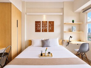 Une chambre d’hôtel moderne équipée d’un lit, de tables de chevet, d’un bureau et d’une fenêtre donnant sur la ville.