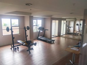 Une salle de sport équipée d’un tapis de course, d’un banc de musculation et d’un support pour barres.