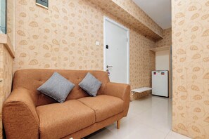 A room with a sofa, a door, and a refrigerator. - Classic Comfortable 1Br At Apartment Green Pramuka City (Jakarta)