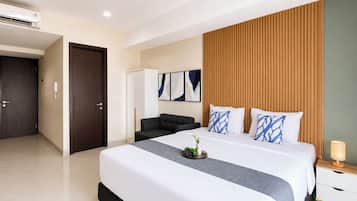 Una habitación de hotel moderna con una cama grande, un armario, una zona de estar y una mesita de noche con lámpara.