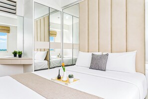 A modern hotel room with a large bed, a bedside table with plants, a mirror, and a view of the outdoors. - Bright And Comfy 2Br Apartment Podomoro Golf View (Depok)