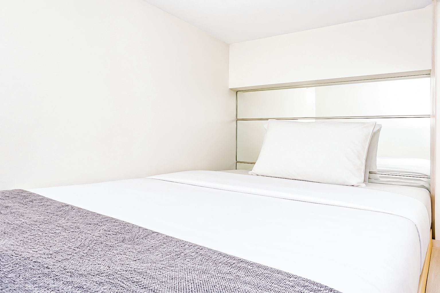 Quarto de hotel com cama, mesa de cabeceira e espelho.