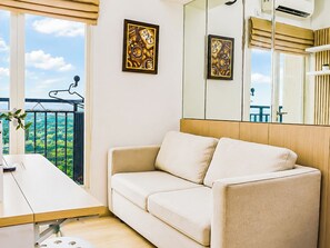 A modern room with a sofa, a dining table, and a view of the sea. - Bright And Comfy 2Br Apartment Podomoro Golf View (Depok)