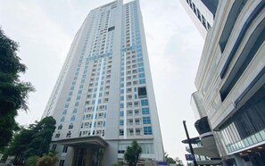 A tall, modern building with a prominent entrance and multiple floors. - 2Br Apartment With Modern Design At Grand Sungkono Lagoon (Surabaya)