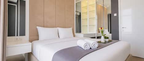 Ein modernes Hotelzimmer mit einem großen Bett, einem Nachttisch, einem Spiegel und einem Kleiderschrank.