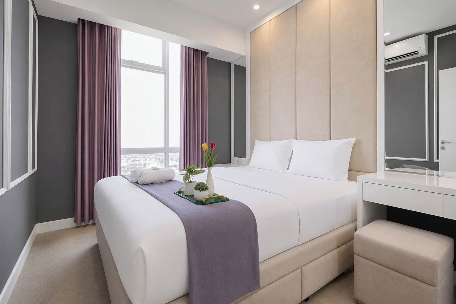 Moderni hotellihuone, jossa on suuri sänky, yöpöytä, peili ja näkymä kaupunkiin.