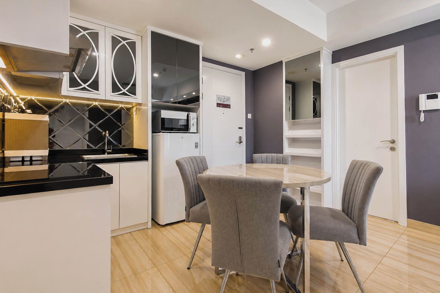 A modern kitchen with a microwave, a built-in oven, and a dining area with a round table and four chairs.