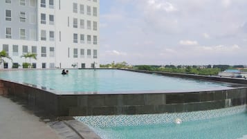 Una piscina con borde de azulejos, rodeada por un muro de piedra bajo.