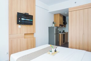 Ein stilvolles Zimmer mit einem Bett, einem kleinen Tisch mit Pflanze und einem an der Wand befestigten Fernseher, der eine Streaming-Oberfläche anzeigt.