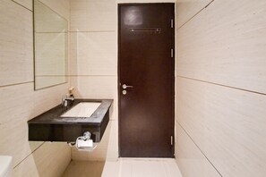 A bathroom with a dark door, a sink with a mirror above it, and a toilet. - Sleek And Comfortable Studio At Apartment Brooklyn Alam Sutera (Tangerang)