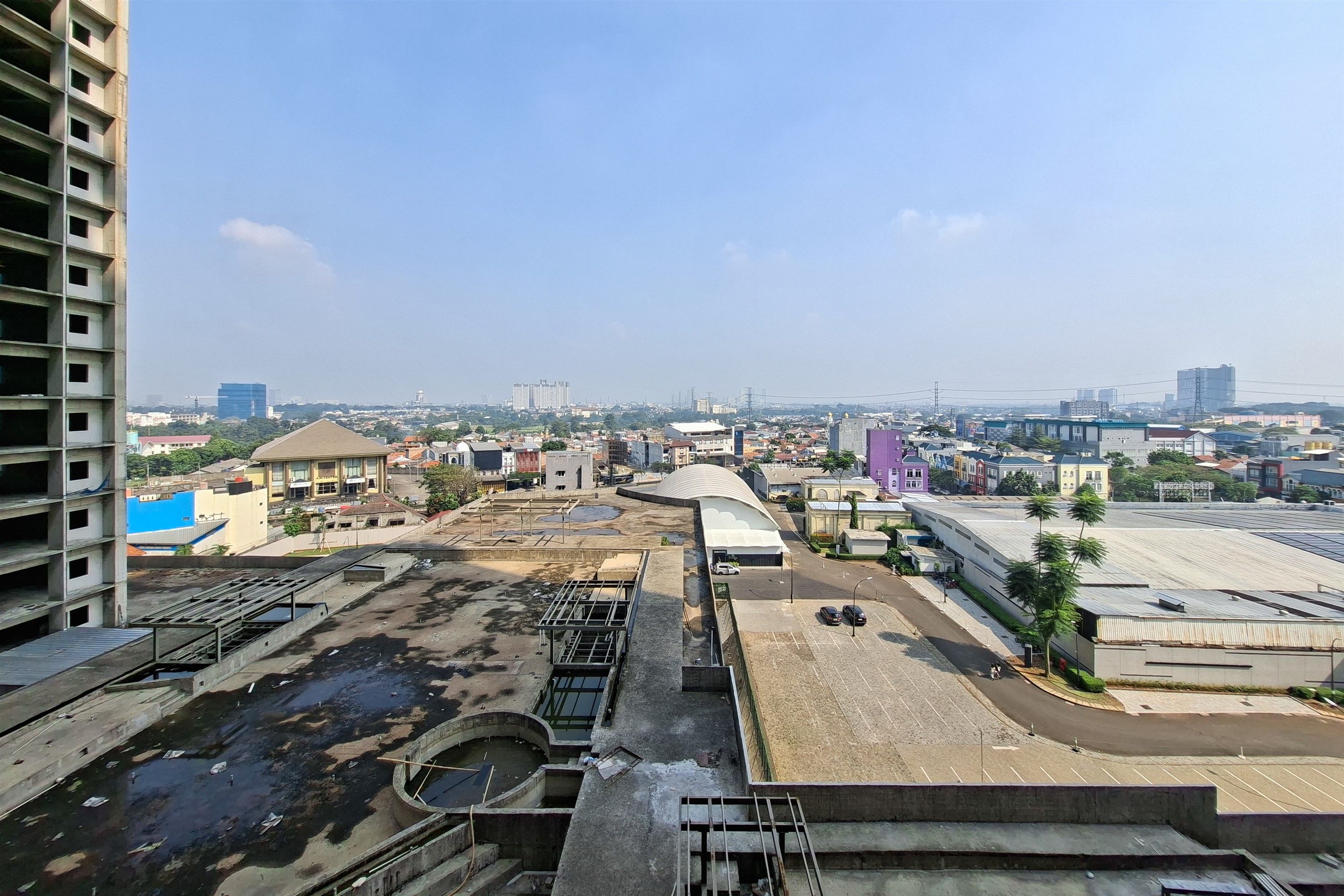 A cityscape with a mix of residential and commercial buildings, including a large multi-story structure on the left and a variety of smaller buildings in the center and right.