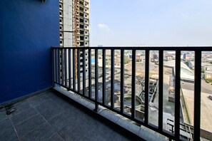A balcony with a black metal railing overlooking a construction site and a cityscape. - Compact Studio Loft Apartment Kingland Avenue (Tangerang)