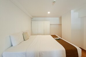 Une chambre à coucher avec un lit, une armoire et une petite table.