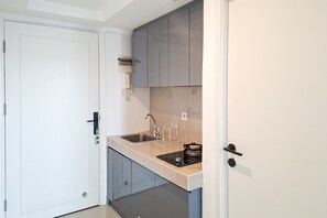 Une cuisine compacte avec une porte blanche, un four encastré et un évier avec un robinet.