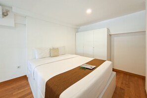 A hotel room with a bed, a wardrobe, and a small table with a magazine. - Compact Studio Loft Apartment Kingland Avenue (Tangerang)