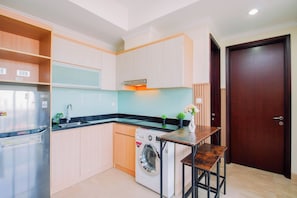 Cocina compacta con lavadora, pileta y una mesa de madera.