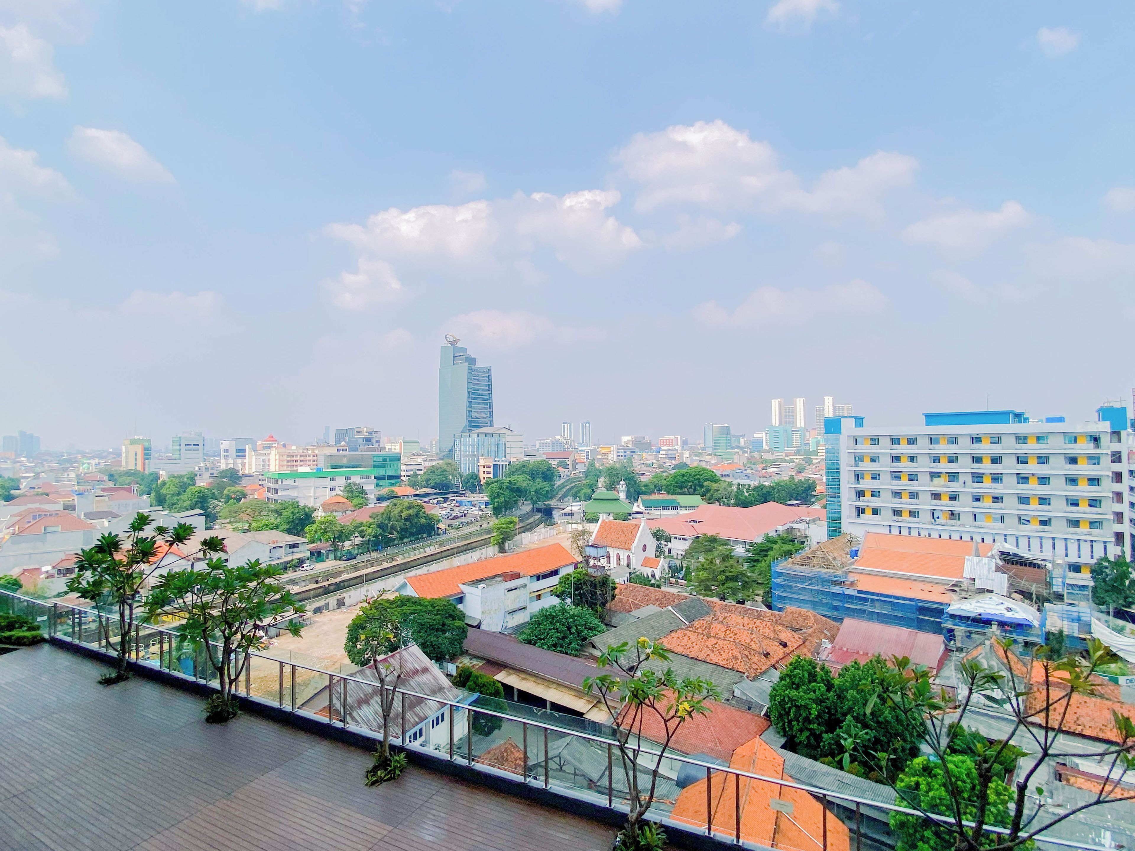 A cityscape with a prominent modern skyscraper, a mix of residential and commercial buildings, and a clear sky.