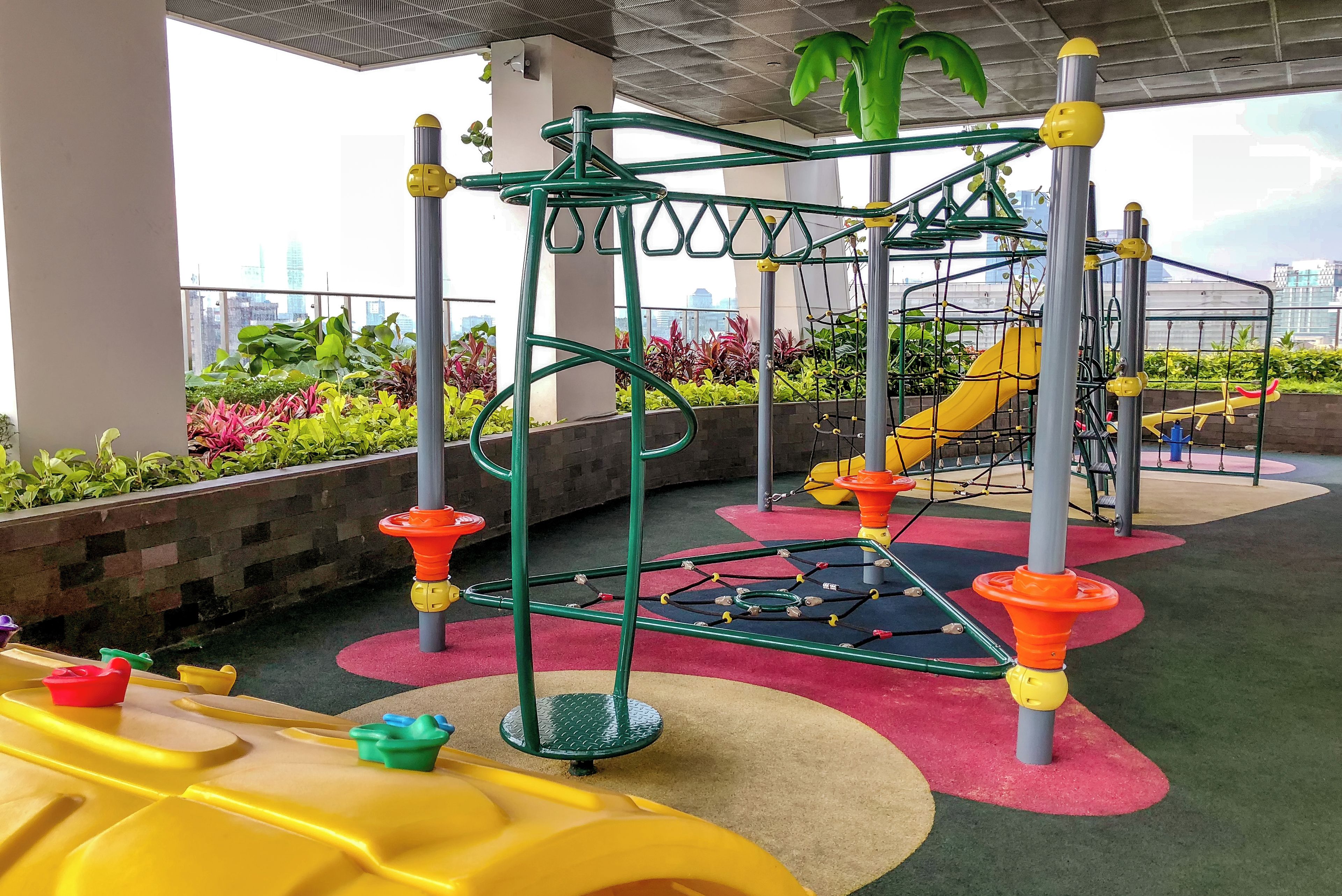 An outdoor play area with a climbing structure, slides, and colorful flooring.