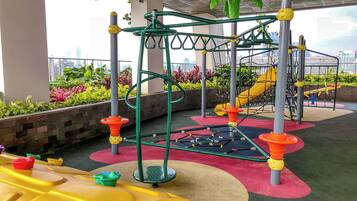 An outdoor play area with a climbing structure, slides, and colorful flooring.