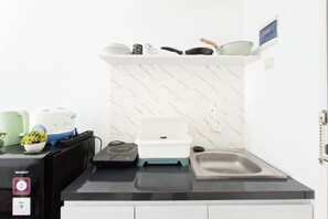 A compact kitchen with a marble backsplash, a sink, and various appliances including a rice cooker and a blender. - Nice Studio For 2 Pax At Urbantown Serpong Apartment (Tangerang)