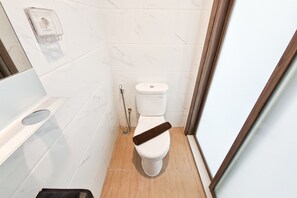 A small, compact bathroom with a toilet, a shower, and a bidet. - Neat And Cozy Studio At Apartment Sky House Alam Sutera (Tangerang)