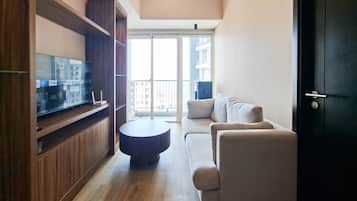 A modern living room with a flat-screen TV on a wooden stand, a round coffee table, and a sofa with cushions.