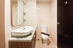A bathroom with a white sink, a mirror, a toilet, and a dark door. - Cozy Ambience 1Br At Casa De Parco Apartment (Tangerang)