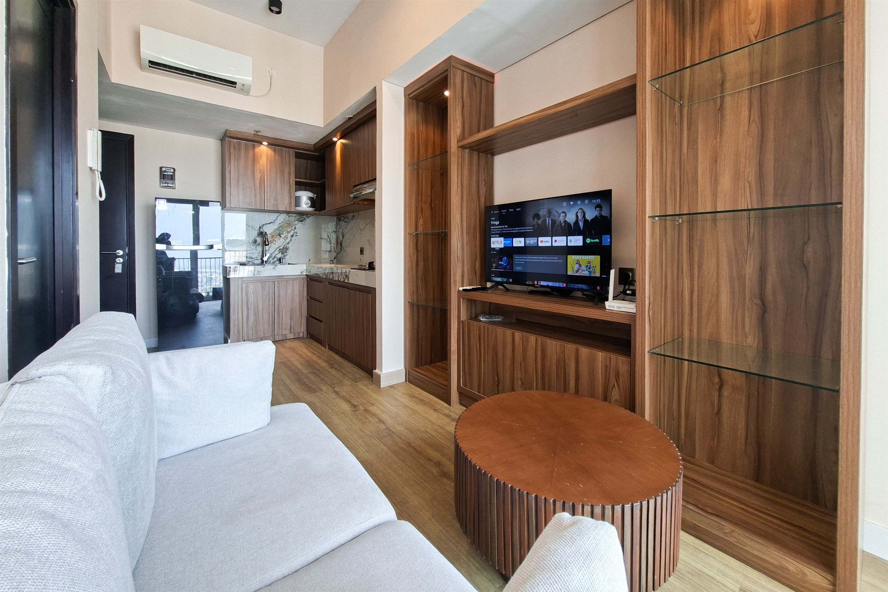 A modern living room with a sofa, a round coffee table, and a television mounted on a wooden wall.