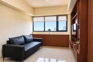 Ein modernes Wohnzimmer mit einem schwarzen Ledersofa, einer Holztrennwand für Unterhaltungselektronik und einem großen Fenster mit Blick auf die Stadt.