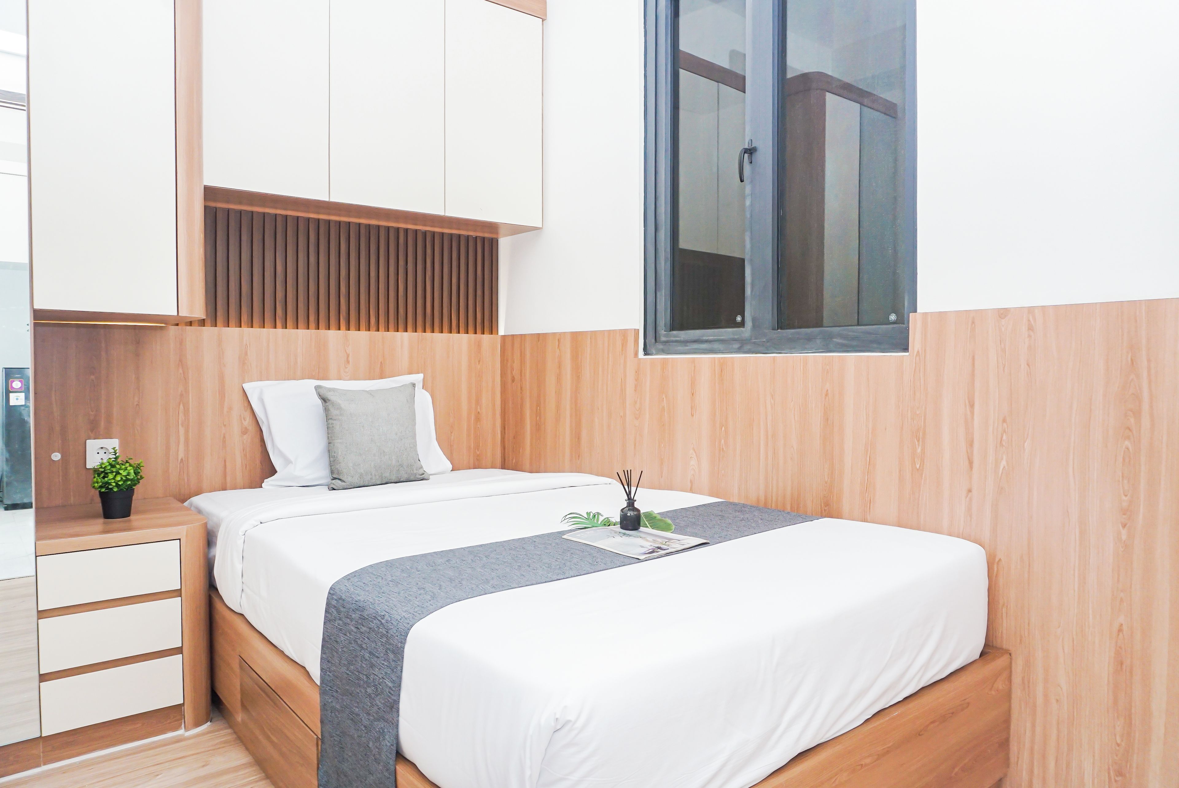 Une chambre à coucher avec un lit, une table de chevet et une fenêtre.