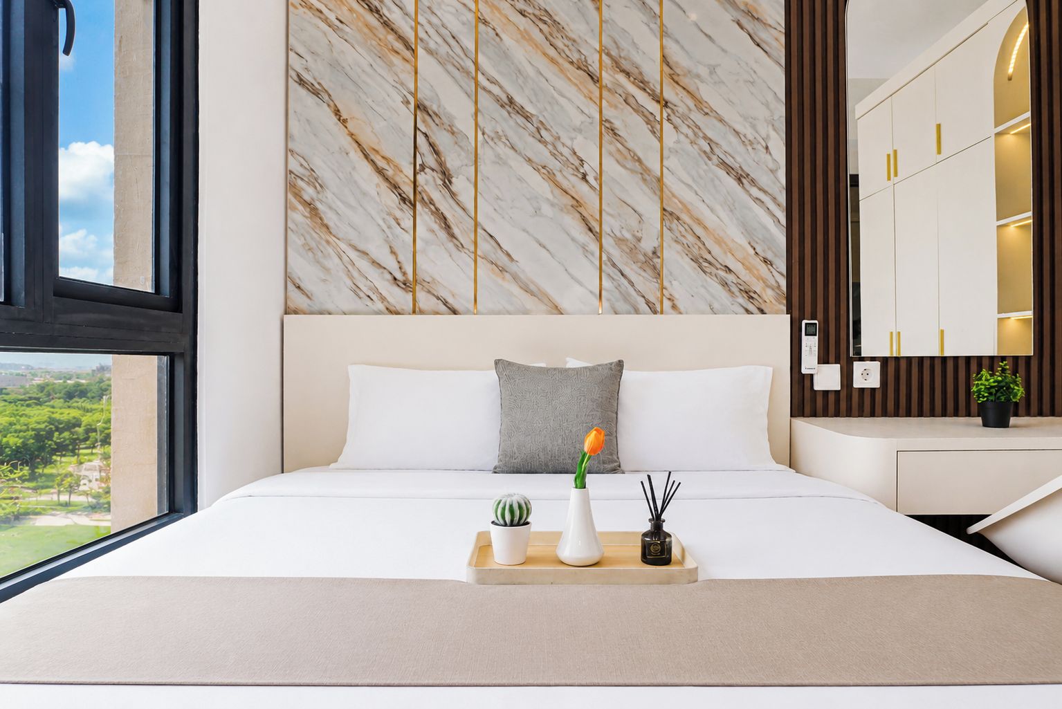 Une chambre d’hôtel moderne avec une tête de lit à motifs de marbre, un lit avec du linge de maison blanc, une table de chevet agrémentée d’une plante et une vue sur la verdure environnante.