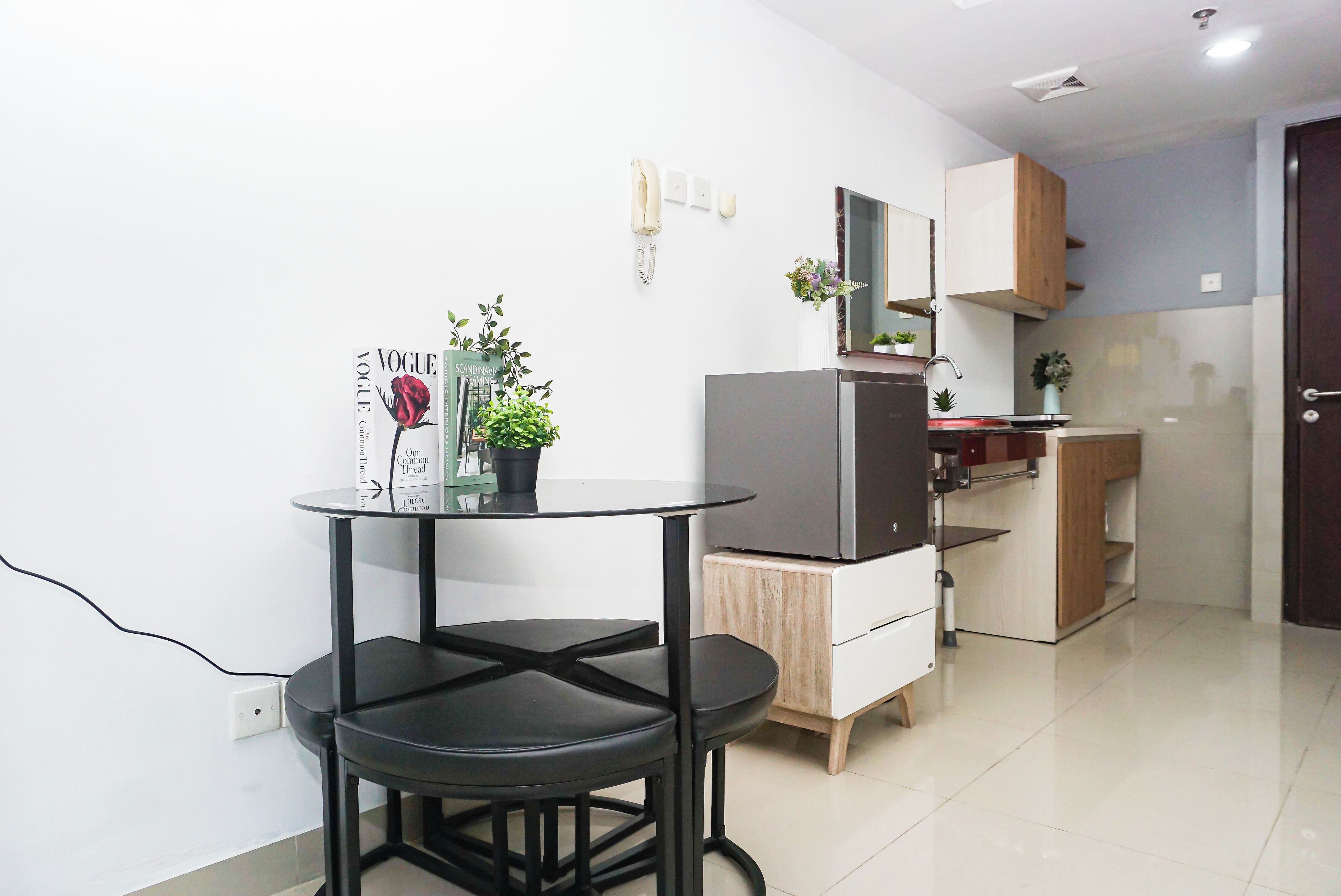 Una cocina compacta con refrigerador, lavamanos y un pequeño comedor con mesa y sillas.