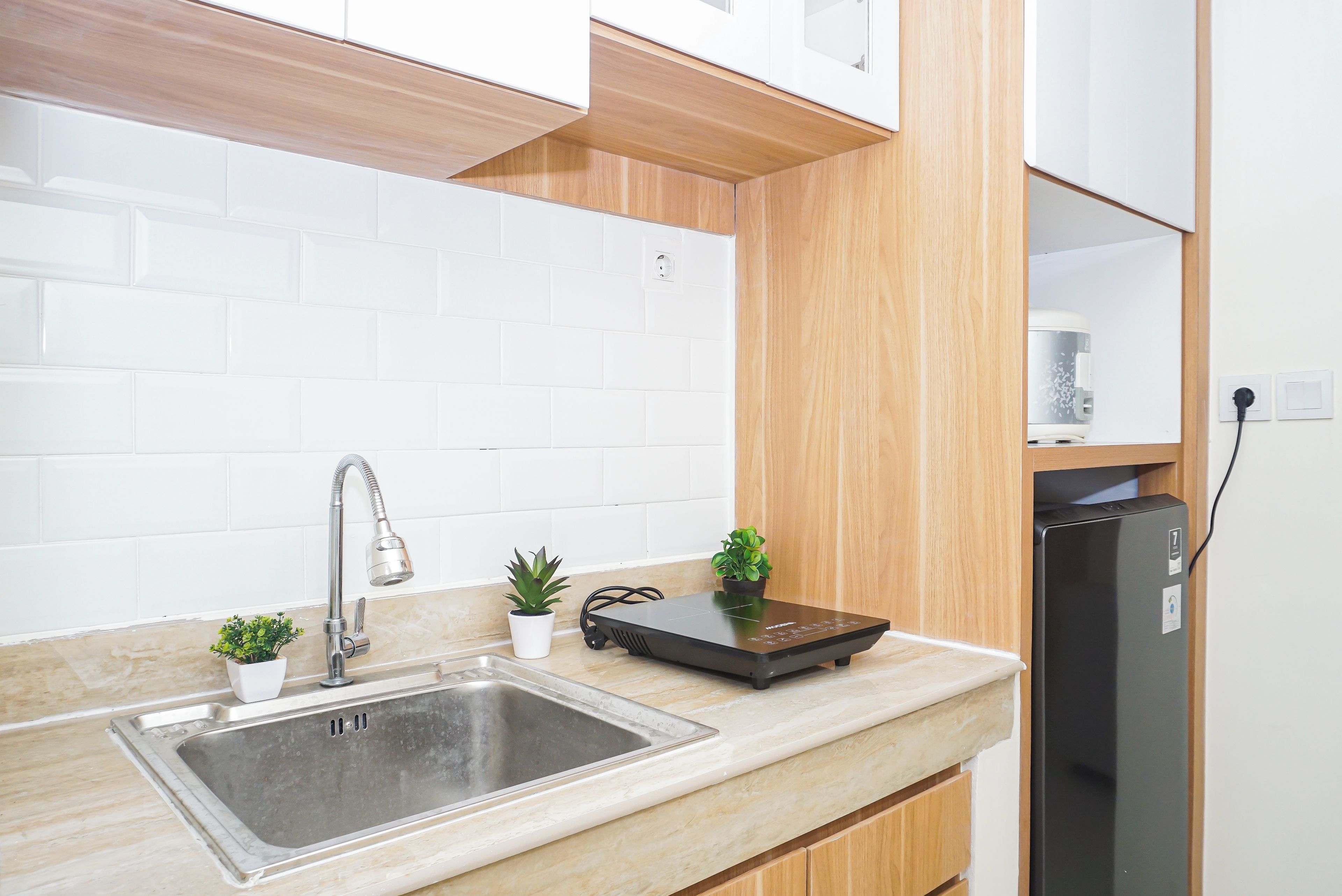 A kitchen with a stainless steel sink, wooden cabinets, a black induction cooktop, and a built-in refrigerator.