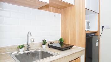 A kitchen with a stainless steel sink, wooden cabinets, a black induction cooktop, and a built-in refrigerator.
