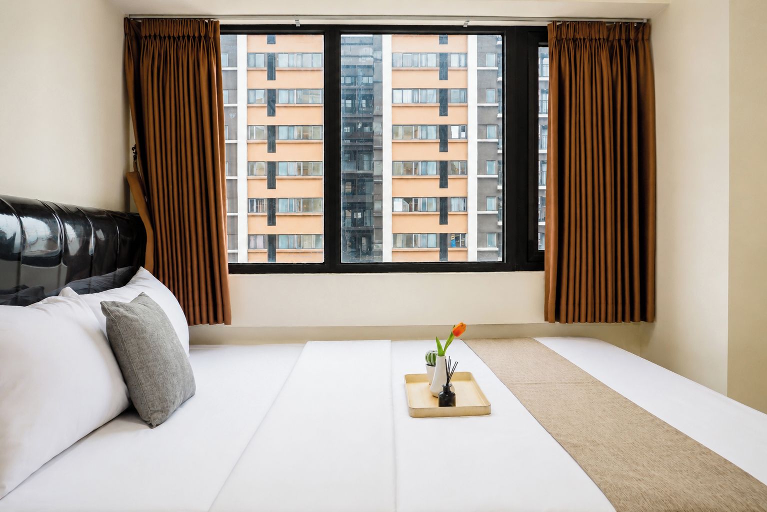 Una habitación de hotel con cama, ventana con cortinas y vista a un edificio.