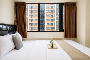 A hotel room with a bed, a window with curtains, and a view of a building. - Warm And Restful 2Br At Apartment Meikarta District 1 (Cikarang)